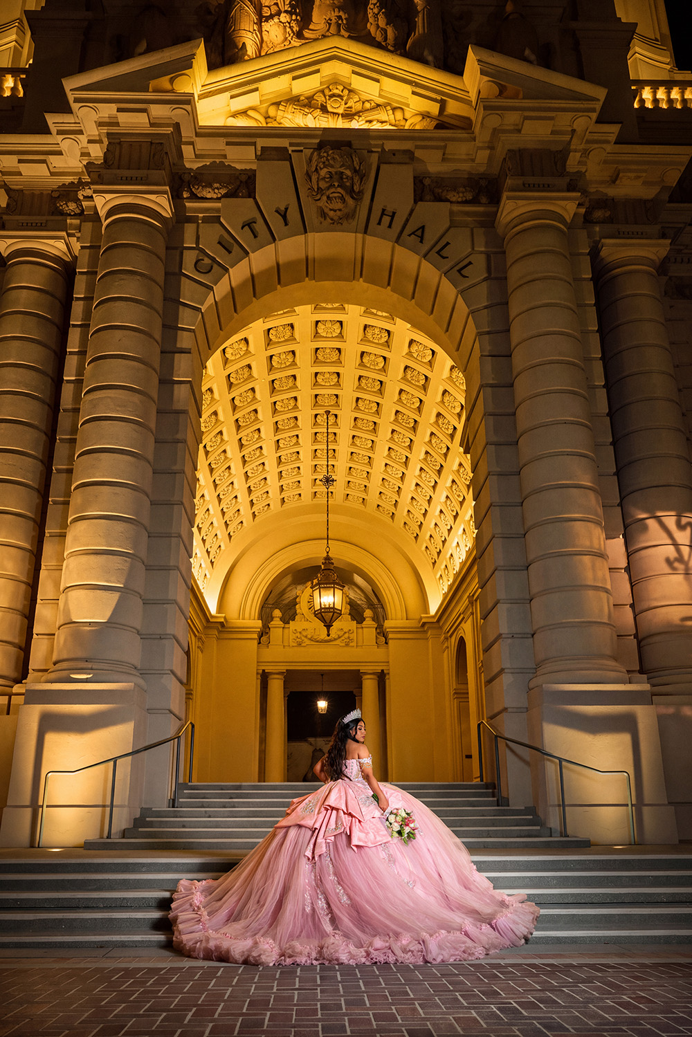 Quinceañera in pink ballgown on the steps of Pasadena City Hall at night